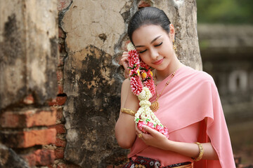 Asian woman in Thai traditional costume standing against wall