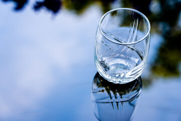 Glass with water and lemon against the background of the reflected sky. Heat