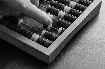 A middle-aged Caucasian man makes calculations on a wooden abacus.