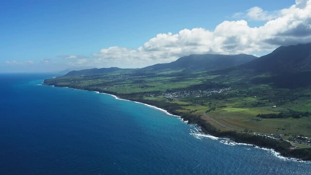 Bird's eye view of the blue sea, black coast, green fields and wooded mountains in Saint Kitts and Nevis