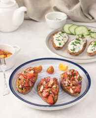 Fresh Mediterranean bruschetta with tomato, olive oil, parsley and red onion on a plate placed on a light background.