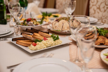 White and dark toasted bread and a mixture of cheese and garlic on a plate among other dishes, salads on a buffet table. Prepared dishes on the table for a birthday celebration in a restaurant