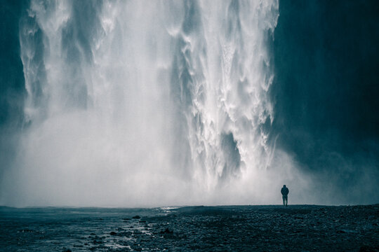 Dramatic view of one person under Skogafoss waterfall in Iceland
