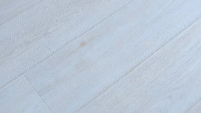 Light grey linoleum surface on floor with wooden pattern in modern interior. Camera in motion. Looks like laminate. Wooden texture, modern material for renovation.