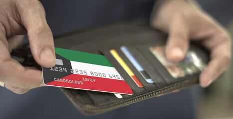 Man pulls plastic bank card with flag of Kuwait out of his wallet, fictional card number
