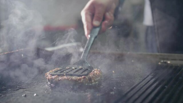 The chef fries a hamburger Patty, fried meat Patty for a Burger, junk food cooked in oil. fried meat