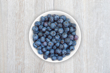 Beverage of fresh blueberry on a plate on a wooden table.