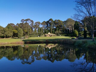 Fototapeta na wymiar Beautiful morning view of a peaceful pond in a park with reflections of deep blue sky and tall trees, Fagan park, Galston, Sydney, New South Wales, Australia