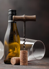 Wine cork with vintage corkscrew on top on wood background with glass and bottle of white wine