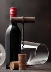 Wine cork with vintage corkscrew on top on wood background with glass and bottle of red wine