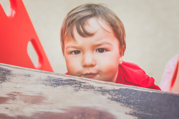 portrait of cute little boy in red t-shirt excitedly playing on playground. concept of happy healthy child