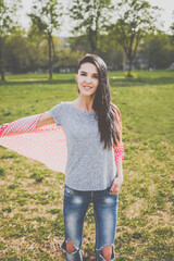 Beautiful hipster girl in red plaid shirt, grey t-shirt and ripped blue jeans in a casual style posing in green nature