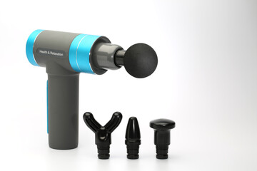 Massage Gun mit kugelförmigem Aufsatz und drei weiteren Massage-Aufsätzen, Nahaufnahme vor...