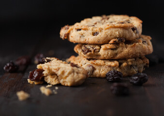Homemade organic oatmeal cookies with raisins and apricots on dark wooden background.