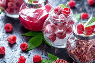 Glass jars with raspberries in different forms. Fresh, freeze dried, frozen, and mashed. Concept of storage types of berries