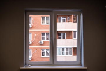 view from the window in a dark room to the street, to the brick house. The concept of loneliness, depression, isolation
