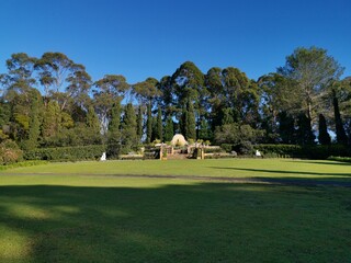 Beautiful morning view of a park with green grass, marble structure, tall trees and deep blue sky, Fagan park, Galston, Sydney, New South Wales, Australia