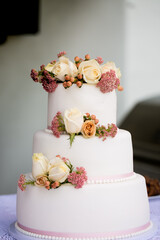 Fototapeta na wymiar smooth white tiered wedding cake with roses