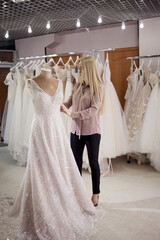 hostess of the wedding salon looks at the wedding dress. Small business, a business woman with her...