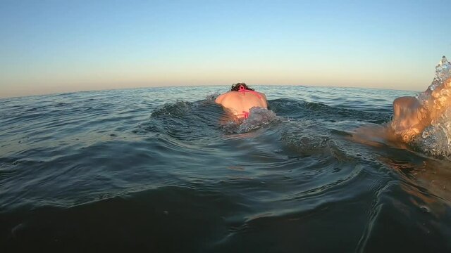 Sexy woman in pink swimsuit dives into the sea