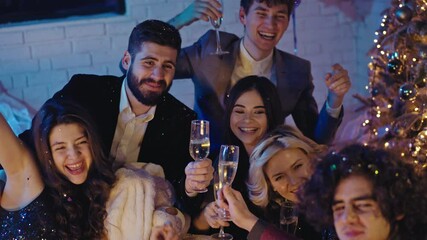 Group of friends celebrating Christmas party together taking selfies and cheers with glasses of champagne all together