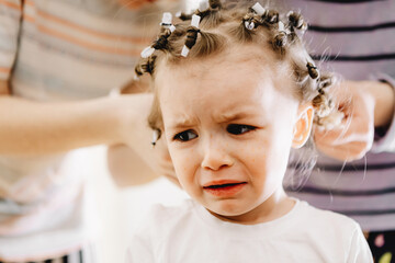 parents unwrap the baby's hair, which they tried to make curly with the help of homemade curlers...
