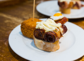 Delicious close up of pintxos/pinchos from San Sebastian (Donostia, Basque Autonomous community, Spain). Typical meal, kind of like spanish tapas. Porc and special sauce on bread.
