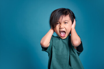 Beautiful asian little kid close his both ear and shouting or screaming.  Empty space in studio...