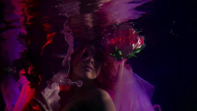 close-up of a woman's face, large flowers and reflections in the surface of dark water. purple contour light