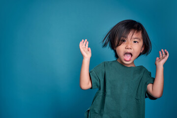 Beautiful asian little kid  shouting or screaming.  Empty space in studio shot isolated on colorful blue background. Education concept for school.