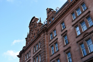 Fototapeta na wymiar Facade of Old Stone Victorian Building against Blue Sky 