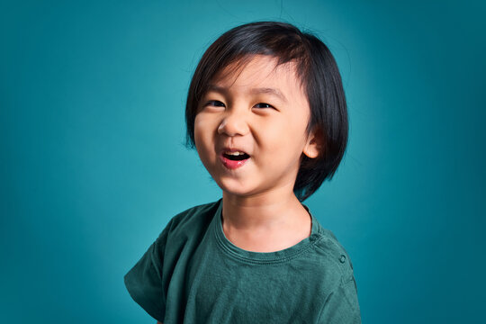 Beautiful asian little kid  smiling and show its excitment.  Empty space in studio shot isolated on colorful blue background. Education concept for school.