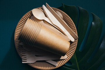 Eco friendly craft paper tableware on green background with monstera leaf