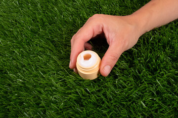 beauty, skin care cosmetics. hand cream, jar with cream in hand on a background of green grass close-up