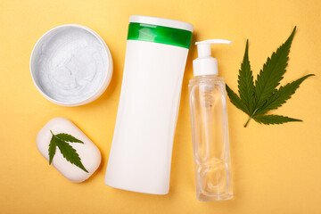 beauty, body care cosmetics with marijuana extract on a yellow background. white bottles with...