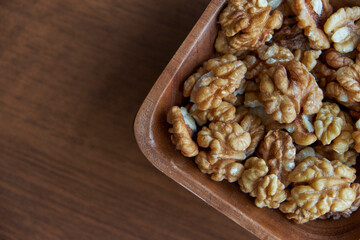 Walnuts kernels on dark desk with color background, Whole walnut in wood vintage bowl.