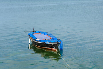 Obraz premium wooden fishing boat with a motor anchored in the sea, calm natural landscape