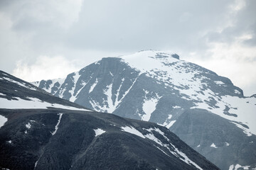 Panoramic shot of beautiful mountain peaks and landscape scenery in spring, with snow capped mountains.