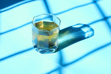 Green Tea in a glass with morning sun rays on blue isolated background, Healthy nutrition green tea in a glass, morning healthy drink