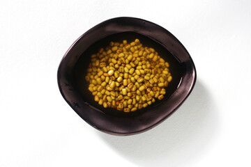 Green bean seeds soaked in a black bowl. Healthy soaked green gram, Green gram in a black bowl on isolated background, green mung beans in water