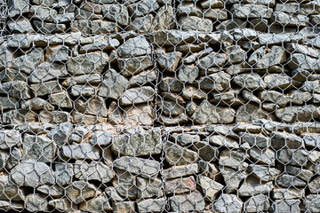 gray stones behind a wire fence. reinforcing structure in construction