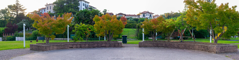 Panorama of public park with trees and children's playground