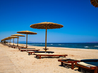 Empty deckchairs and parasols on empty beach
