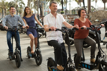 mature parents with older children enjoy a ride on electric scooters