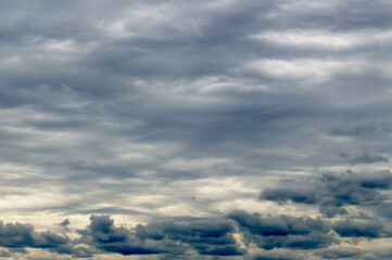 The gloomy sky covered with dense clouds of dark gray color. The clouds are interestingly located on the background of lighter clouds.