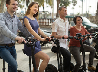 friends of tourists of different generations enjoy a ride on electric scooters