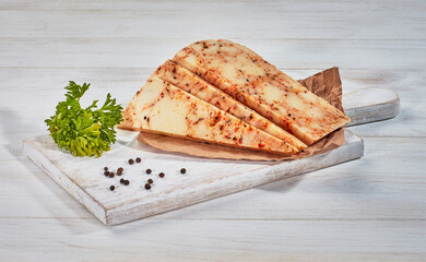 Sliced cheese with herbs on wooden cutting-board