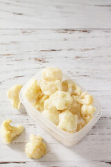 Healthy frozen food for the winter. Containers with frozen cauliflower. Copy space.