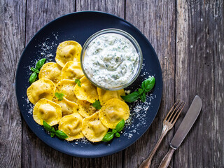 Delicious ravioli with mushrooms and cream sauce on wooden table