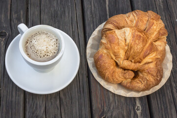 Fresh bakery. Cozy background for a coffee shop. Black coffee and croissant. French breakfast. Wooden table. Aromatic drink. Restaurant theme. Morning meal. Office food.